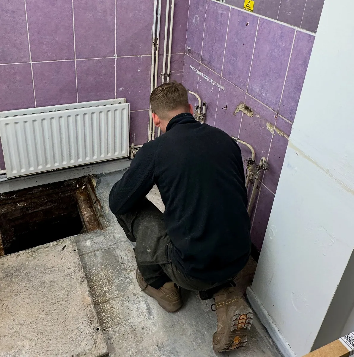 Heating engineer diagnosing a faulty boiler with a multimeter